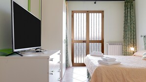 Ein Hotelzimmer mit Bett, Fernseher auf einem Schminktisch, Heizkörper und einem Fenster mit Vorhängen.