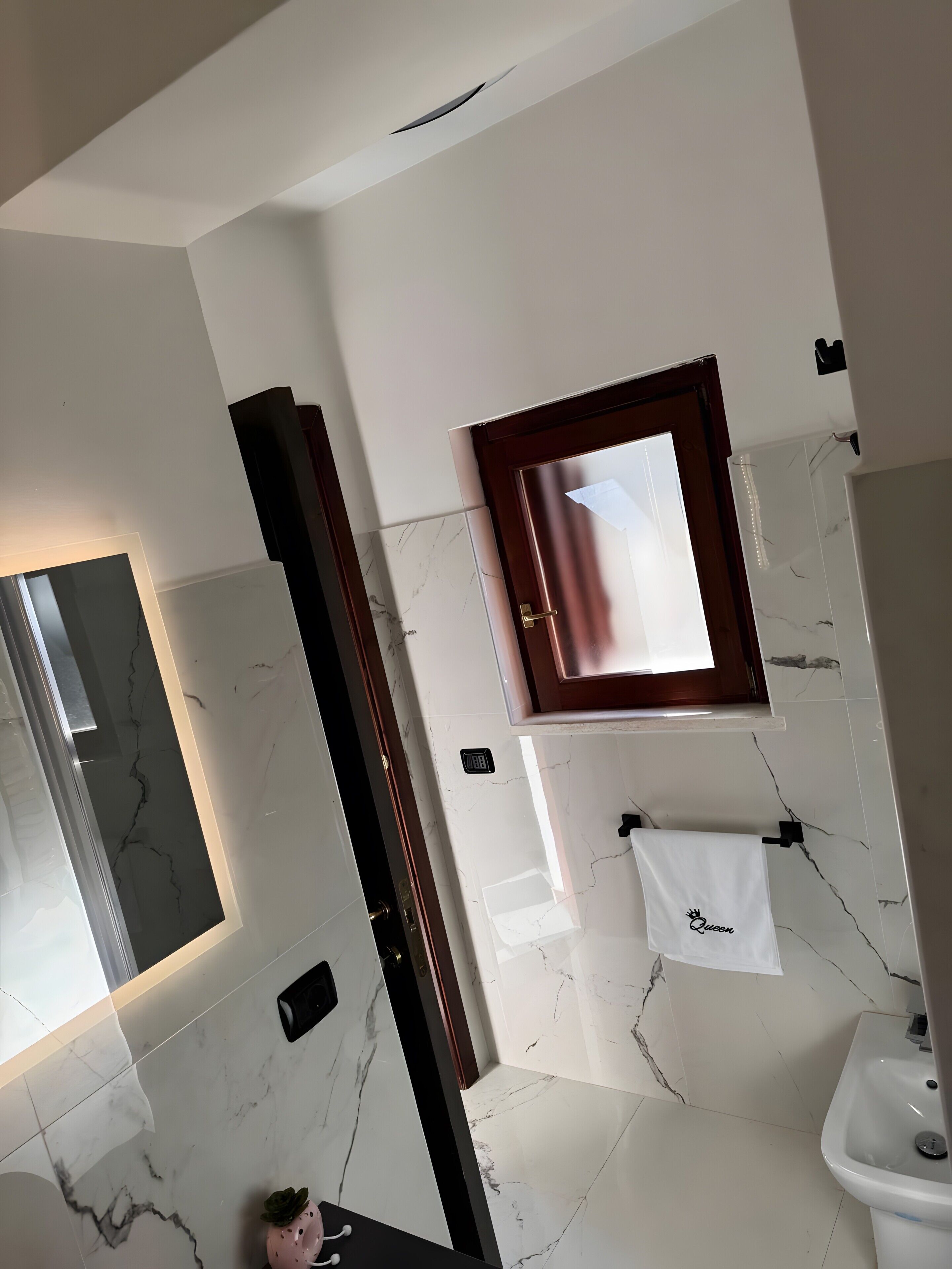 Une salle de bain avec un miroir, un lavabo, un porte-serviettes et une fenêtre.
