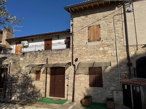 A stone building with a wooden door, a balcony with a railing, and a small awning over the entrance. - Holiday Home 'Genghetta' with Garden, Wi-Fi and Air Conditioning (Rivotorto)