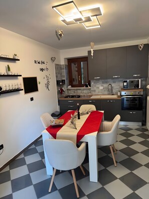 Una cocina moderna con comedor, con piso a cuadros, mantel rojo y un reloj en la pared.