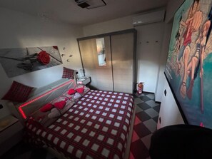 A bedroom with a bed, a nightstand, a dresser, a mirror, and a wall with a poster.