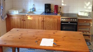 Una cocina con armarios de madera, una encimera, un fregadero, una estufa y una mesa comedor con bancos.