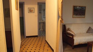 Un pasillo estrecho con suelo a cuadros que conduce a un baño y un dormitorio con cama y un cuadro en la pared.