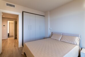 A bedroom with a bed, a wardrobe, and a door leading to another room. - Villa Pignone 12 (Genova)