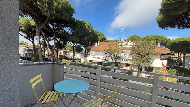 Ein Balkon mit Tisch und Stühlen, der auf einen Wohnbereich mit Bäumen und Häusern blickt.