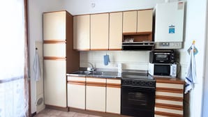 Eine kleine Küche mit Spüle, Herd, Mikrowelle und Kühlschrank.