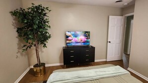 A bedroom with a bed, a dresser, a television, and a potted plant. - 2BR Near Sherman College & Shops (Boiling Springs)