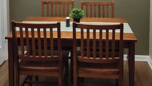 A dining area with a wooden table and chairs, a ceiling light fixture, and a green wall. - 2BR Near Sherman College & Shops (Boiling Springs)
