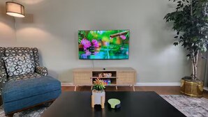 A living room with a sofa, coffee table, TV, and a plant. - 2BR Near Sherman College & Shops (Boiling Springs)