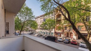 Un balcó amb vista a un carrer ple de cotxes aparcats i edificis.
