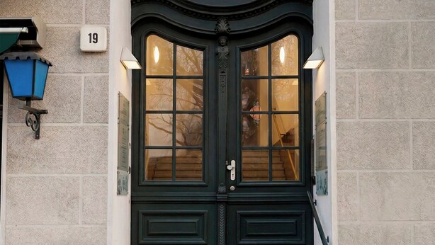 Entrada d'un edifici amb una porta doble, escales i un rètol amb el número 19.