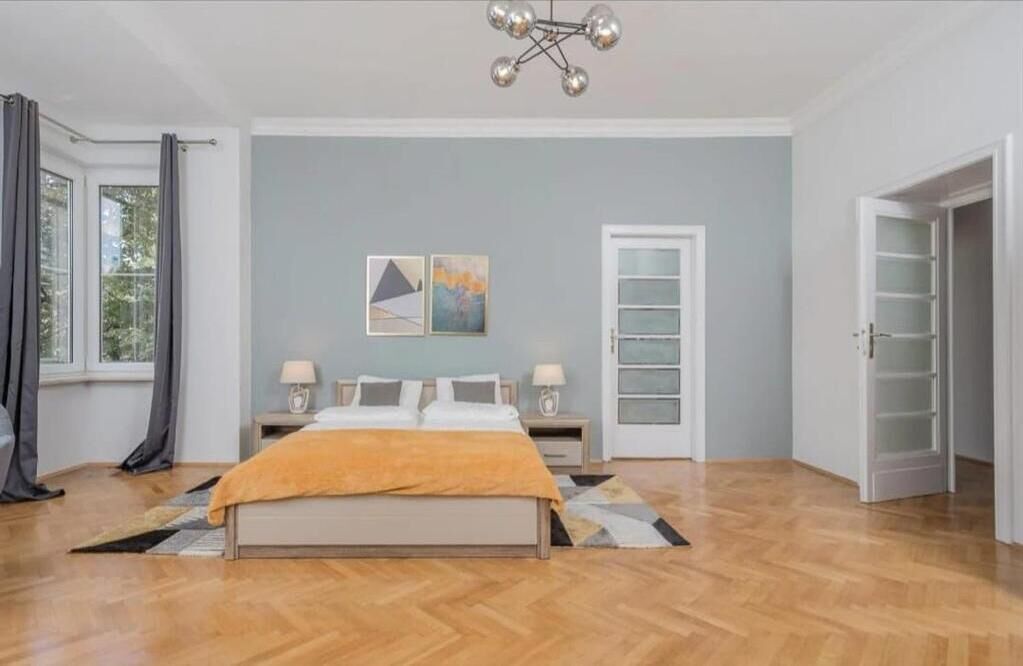 Une chambre à coucher avec un lit, des tables de chevet, une armoire et une fenêtre avec des rideaux.