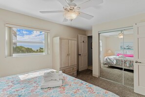 Ein Schlafzimmer mit Bett, Kleiderschrank, Spiegel und Deckenventilator.