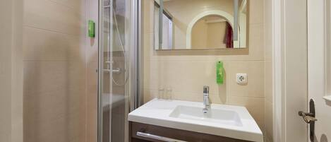 A modern bathroom with a glass-enclosed shower, a white sink, and a mirror above it.