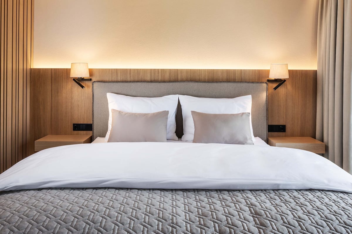 Une chambre d’hôtel avec un grand lit, deux lampes de chevet et une tête de lit en bois.