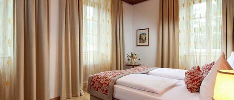 Una habitación de hotel con una cama grande, techo de madera y una araña.