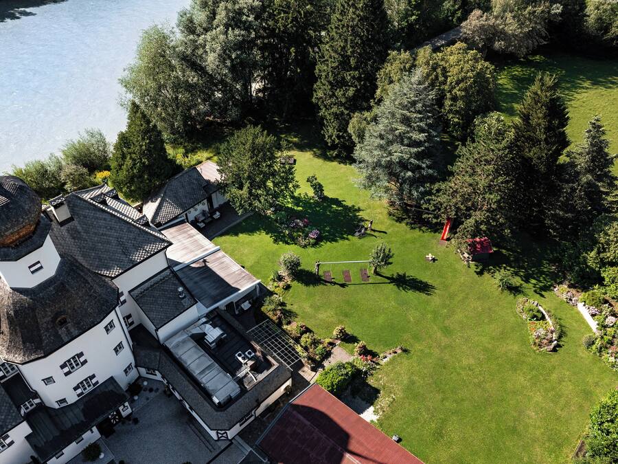 Vue aérienne d’une propriété comprenant un grand bâtiment doté d’une tour imposante, une pelouse bien entretenue et des arbres environnants.