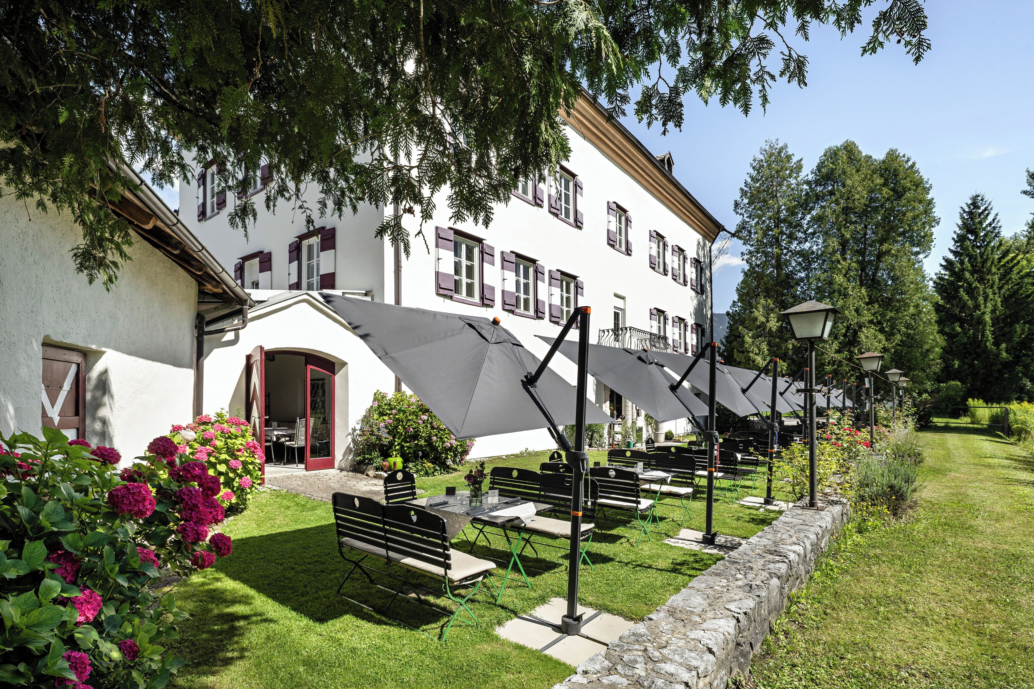 A building with outdoor seating, a stone wall, and a well-maintained lawn.
