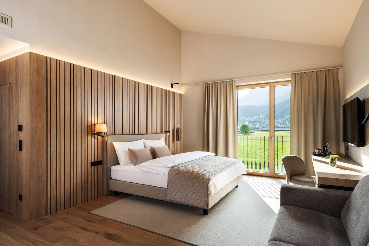 Une chambre moderne avec un grand lit, un bureau avec une chaise et un téléviseur.