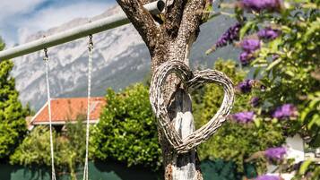 Ein Baum mit Herz-Dekoration, einer Schaukel und einem Berg im Hintergrund.