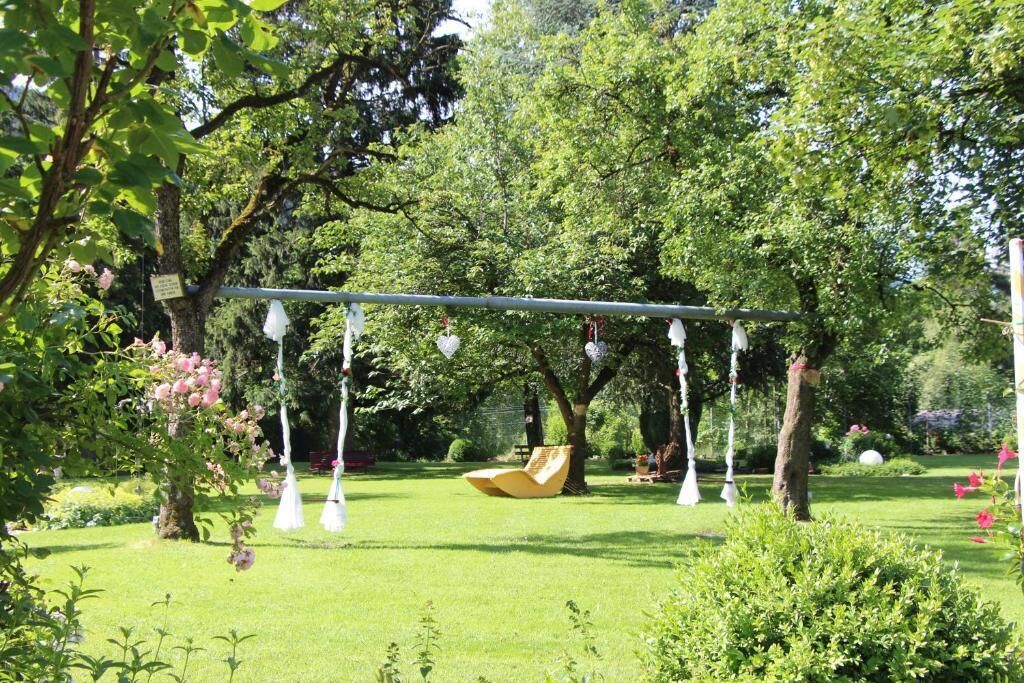 Un jardín con un columpio, un banco amarillo y luces colgantes.