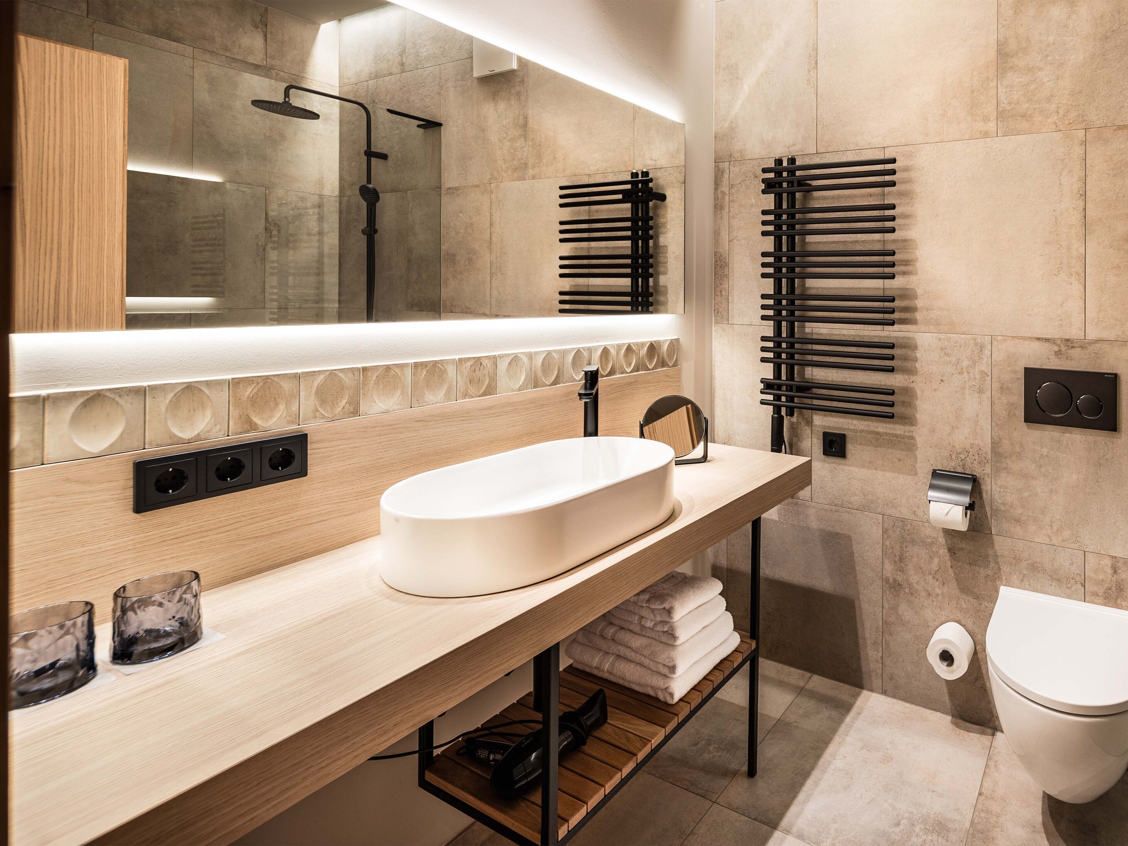 Un bagno moderno con uno specchio grande, un lavabo indipendente, un porta asciugamani e un water.