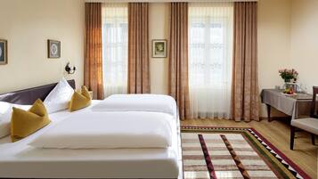 A hotel room with a large bed, a small table with a vase, and a chair.