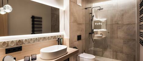 A modern bathroom with a large mirror, a sink, a toilet, and a glass-enclosed shower.