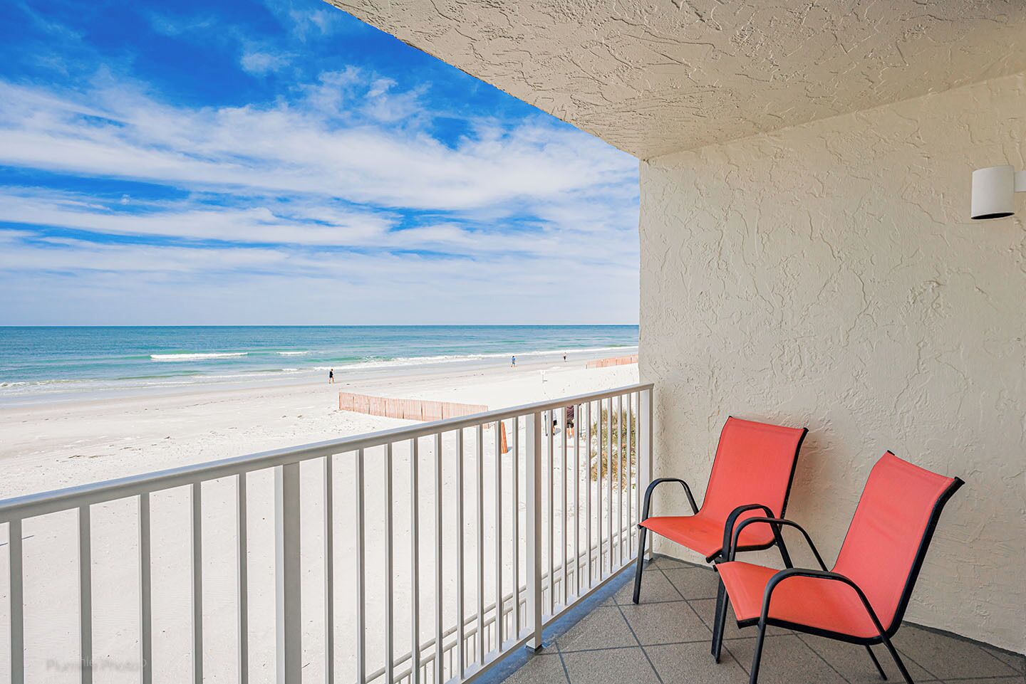 A balcony with a view of the beach and ocean.