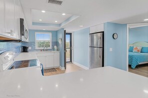 A modern kitchen with white cabinets, a stainless steel refrigerator, and a built-in stove. - Beachfront Oasis-Gulf View-Balcony-Heated Pool (Indian Shores)