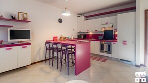 Eine moderne Küche mit Kochinsel, Barhocker, Flachbildfernseher und Mikrowelle.