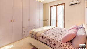 Ein Schlafzimmer mit Bett, Kleiderschrank, Heizkörper und Fenster.