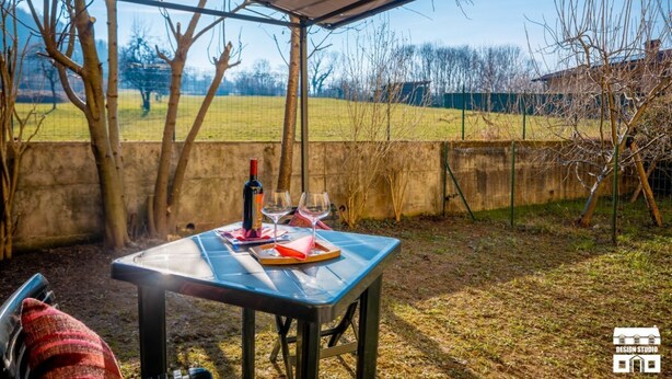 Eine Terrasse im Freien mit einem für zwei Personen gedeckten Tisch, einer Weinflasche und Gläsern.