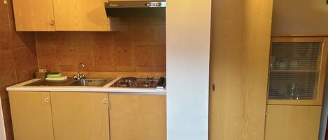 A kitchen with wooden cabinets, a stainless steel sink, and a gas stove.