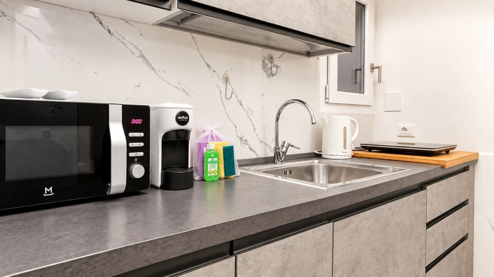 A modern kitchen with a microwave, coffee maker, and a sink.
