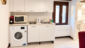 A compact kitchen with a microwave, coffee maker, and washing machine. - Appartamento Ca’De la Madonna by Ca-Sa Check (Venezia)