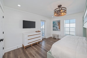 A bedroom with a bed, a dresser, a television, and a painting. - Reefwood - Sleeps 21 - 2 Blocks to the Beach! (Destin)