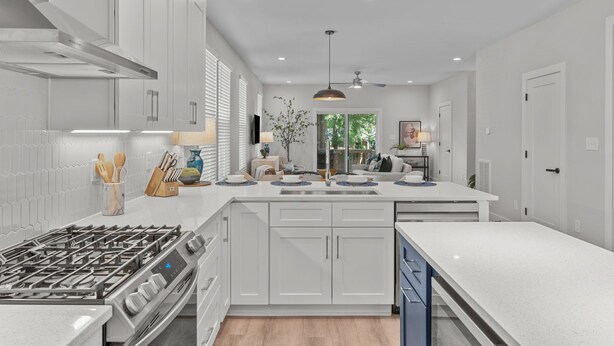 A modern kitchen with white cabinetry, a central island, and a built-in stove. - Design-Forward 3BR: King Suite, Pet-Friendly Fenced Yard, Office, Near Greenway (Raleigh)
