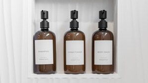 Three bottles of shampoo, conditioner, and body wash in a white shelf. - Design-Forward 3BR: King Suite, Pet-Friendly Fenced Yard, Office, Near Greenway (Raleigh)