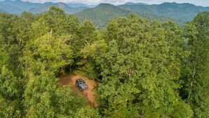 An aerial view of a forested area with a vehicle parked on a dirt path. - Holly Hideaway | Cozy Yurt | Pet Friendly & Trails (Cullowhee)