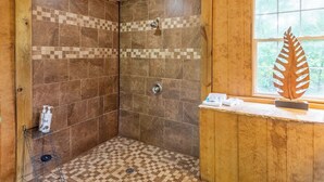 A shower with checkered tiles, wooden walls, and a window with a leaf decoration. - Holly Hideaway | Cozy Yurt | Pet Friendly & Trails (Cullowhee)
