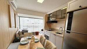 Una cocina compacta con comedor, horno empotrado y refrigerador.