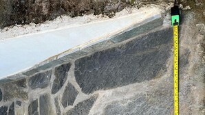 Paredes de pedra com uma fita métrica mostrando seu comprimento.
