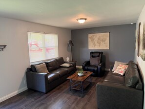 A living room with a dark brown leather sofa, a coffee table, and a massage chair. - PERFECT MIAMI STAY 4-bedroom 2 bath with luxury shower in O (Oxford)