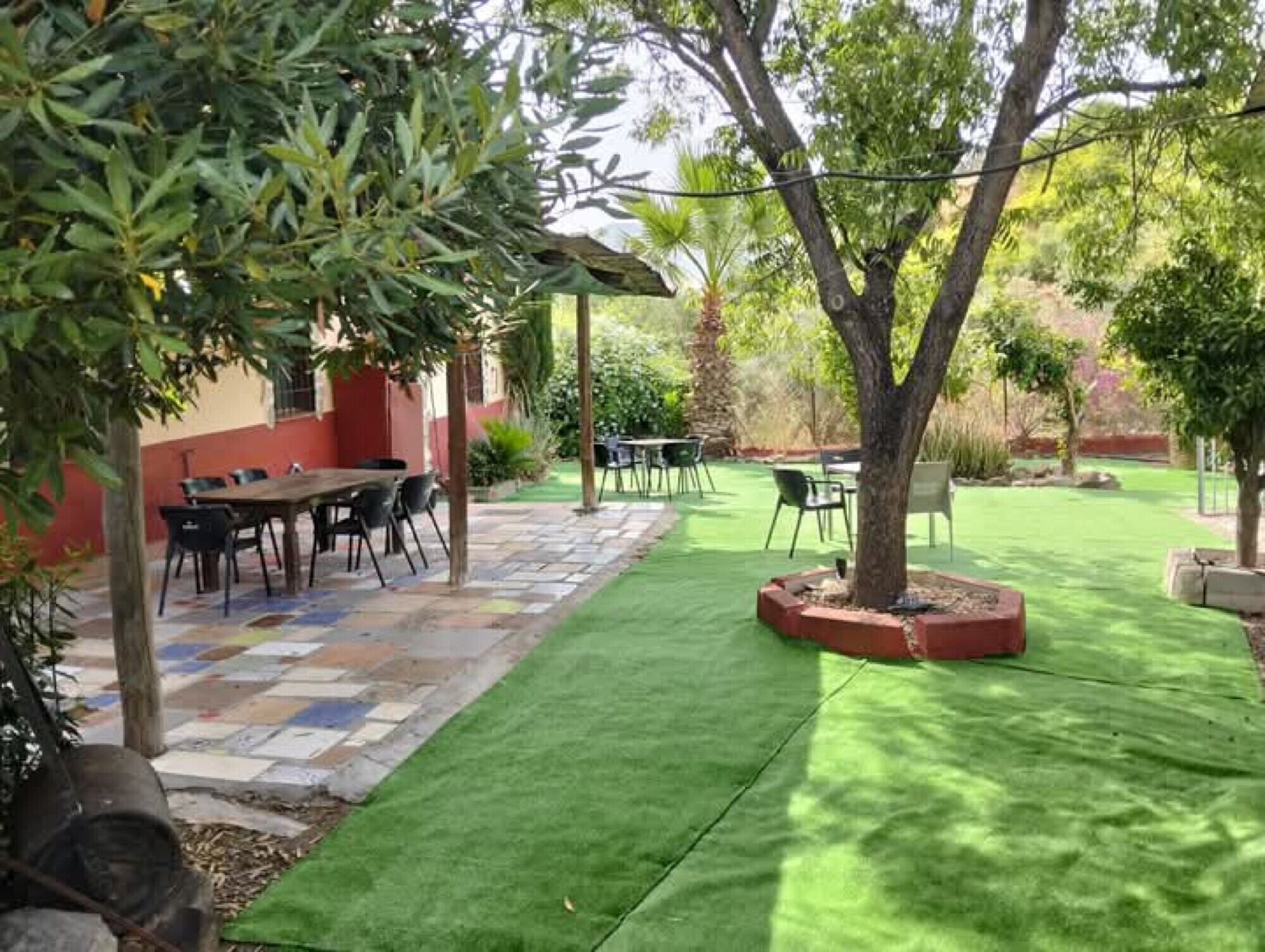 A patio area with a table and chairs, surrounded by a well-maintained lawn and trees.