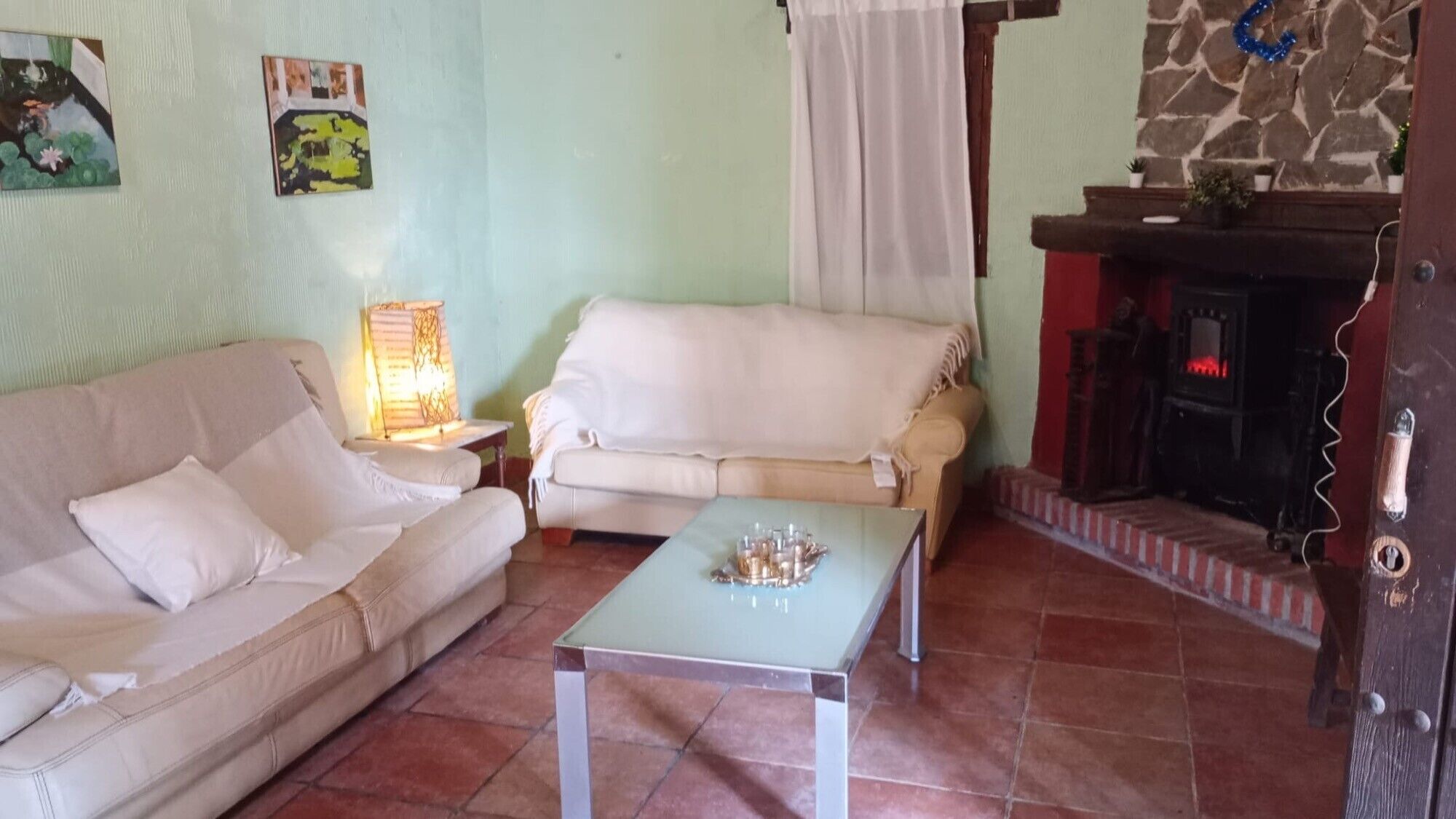 Una sala de estar con sofá, mesa, lámpara y chimenea.