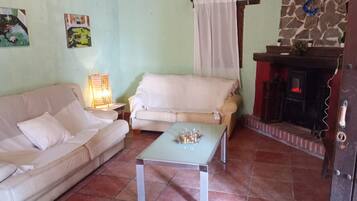 Una sala de estar con sofá, mesa, lámpara y chimenea.