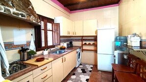Eine kleine Küche mit Gaskochfeld, Waschmaschine und Kühlschrank.