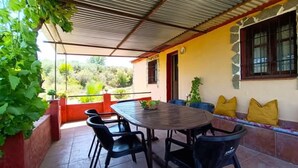 Eine Terrasse mit Tisch und Stühlen, eine gelbe Wand und Blick ins Grüne.