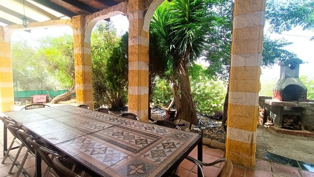 An outdoor patio with a patterned table and chairs, a stone oven, and a view of trees. - Country House 'Cucazorra' with Mountain View, Wi-Fi and Air Conditioning (Málaga)